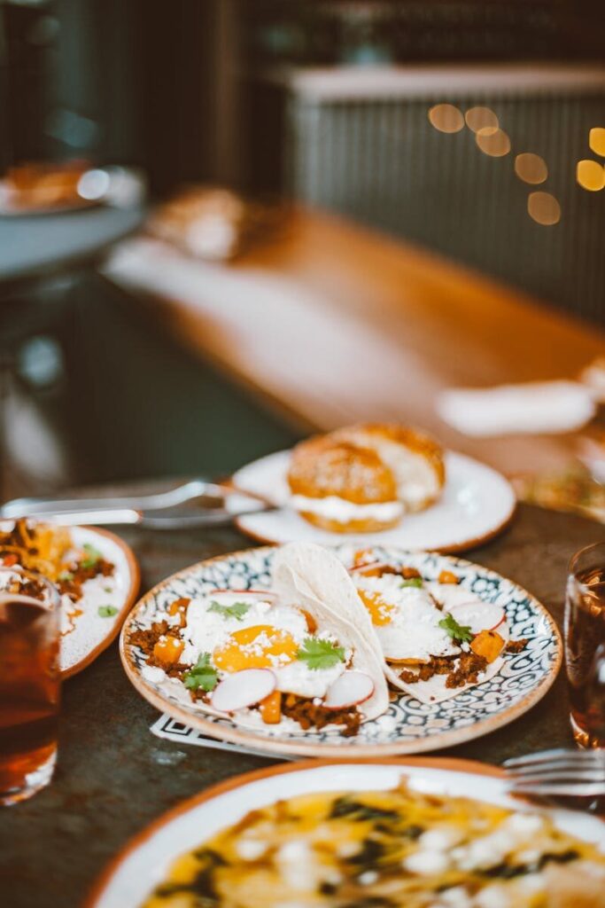 Elegant breakfast spread with sunny side up eggs, wraps, and drinks on a ceramic plate.